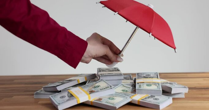 Insurance agent holds umbrella and keep money safe