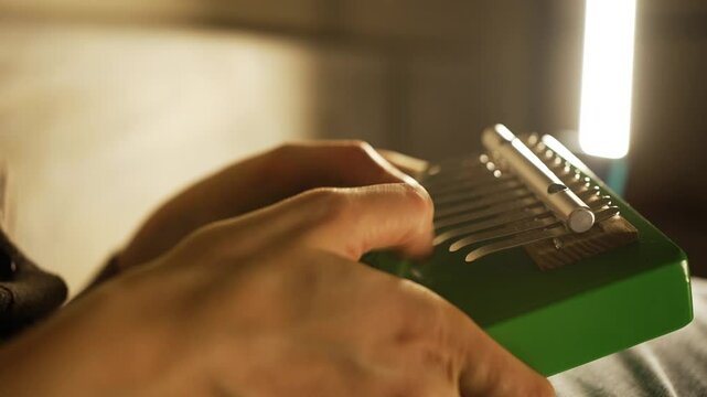 Musician's hands gently caressing kalimba tines, creating soft, mesmerizing melodies under warm indoor lighting, showcasing intimate musical moment