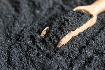 Charcoal powder in wooden shovel with charcoal powder background.