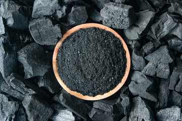 Charcoal powder in wooden plate with charcoal background. Top view