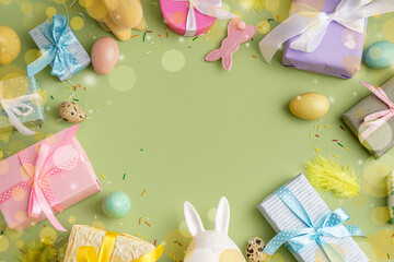Frame made of painted Easter eggs with gift boxes and bunnies on green background