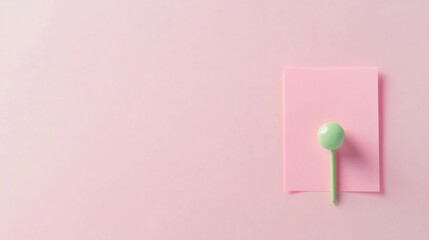 A small pastel pink note pinned with a decorative green push pin, adding a vibrant touch, isolated on white