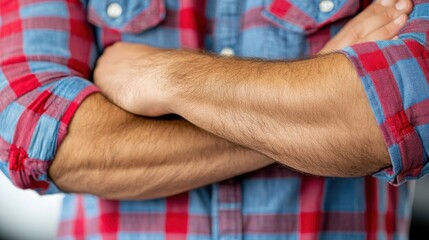 Close-up of a man with crossed arms in a plaid shirt.