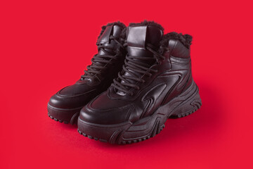 Winter warm black leather sneakers isolated on red background