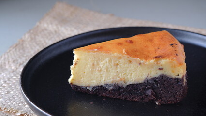 A slice of Brownies Basque Cheesecake on a black plate.