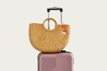 Suitcase with stylish beach bag on white background