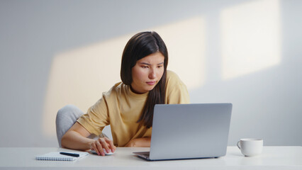 Focused freelancer woman work using computer laptop sit at home. Busy serious girl type wear yellow t shirt. Remote education during covid 19 corona virus. Distance job start up Online internet career