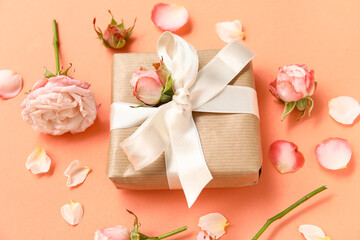 Gift box with roses and petals on orange background