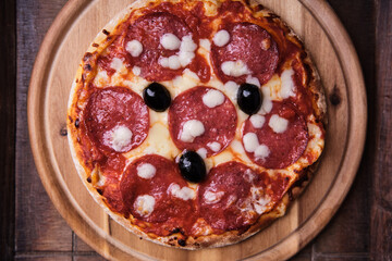Pizza with salami and mozzarella cheese. Wooden background. Soft focus. Top view. Close up.
