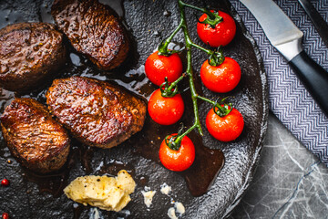Filet mignon steaks with cherry tomatoes on a black mica plate. Top view Close-up.
