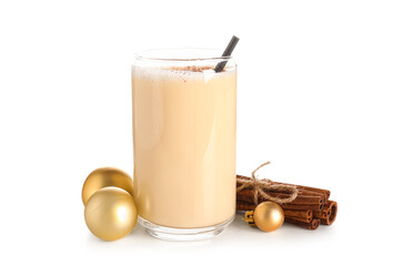 Glass of tasty eggnog cocktail with cinnamon and Christmas balls on white background