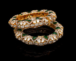 Diamond bangle with many stones and Gems on a reflective black background.