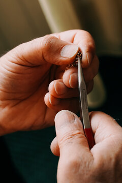 Jeweler making a chain of rings. Close up of the hands of a goldsmith. Concept: jewelry, gold, fashion. Vertical photo