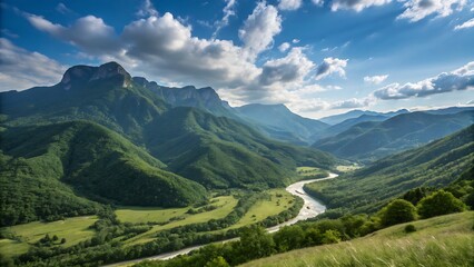 Fototapeta premium landscape in the mountains A panoramic view of a mountain range with lush green valleys and a winding river under a bright blue sky with scattered clouds.