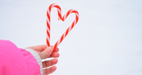 Candy cane heart emerges in crisp winter space, where minimal background heightens sweet shape....