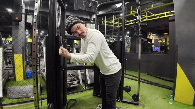  Young Man Doing Triceps Pushdowns with a Cable in the Gym, Featuring Machines and Beautiful Lighting in the Background, Shot in Slow Motion