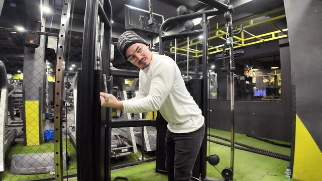 Young Man Doing Triceps Pushdowns with a Cable in the Gym, Set Against a Background of Equipment and Elegant Lighting, Captured in Slow Motion