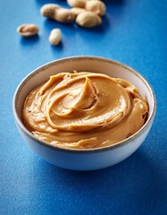 Fresh healthy peanut butter in bowl on blue background