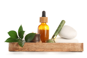 Wooden board with bottle of essential oil, facial massage tool, spa stones and plant branch on white background