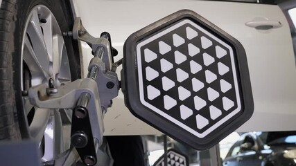 Diagnostics and balancing of wheels on a lift in close-up at a modern service station. The car is moving slowly with wheel balancing equipment.