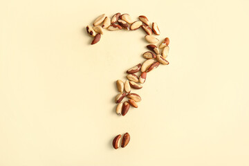 Question mark made of peanuts on color background
