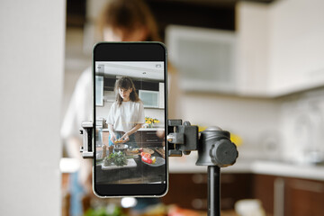 Woman recording video recipe while cooking in the kitchen