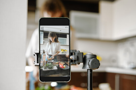 Woman recording video recipe while cooking in the kitchen