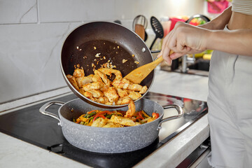 Stir-frying chicken and vegetables in modern kitchen with a focus on fresh ingredients