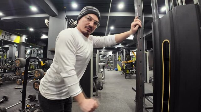 Young Man Performing Single-Arm Triceps Cable Pushdown in the Gym, with Machines and Mirrors in the Background, in an Empty Gym