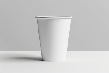 Single white disposable paper cup on white surface.