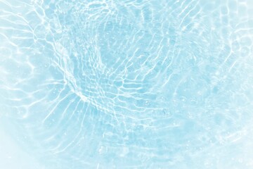 Bluewater waves on the surface ripples blurred. Defocus blurred transparent blue colored clear calm water surface texture with splash and bubbles. Water waves with shining pattern texture background.