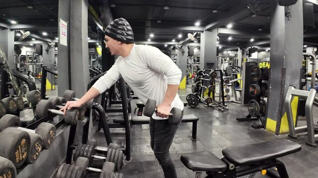  Young Man Performing Triceps Kickback with a Dumbbell in the Gym, Standing Straight with One Hand on the Dumbbell Rack and Exercising with the Other Hand, Captured in Slow Motion