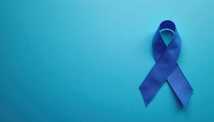 Blue ribbon on deep blue background, top view with space for message. Cancer awareness concept.