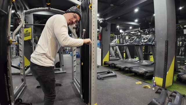 Young Man Performing Triceps Pushdowns with Cable in an Empty Gym, with Treadmills, Maintenance Parts, and Cinematic Lighting, Captured in Slow Motion