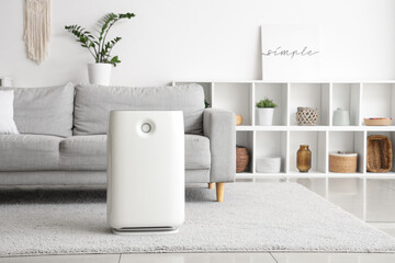 Modern air purifier on carpet in living room interior