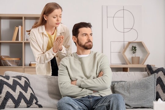Young woman apologizing to her husband at home