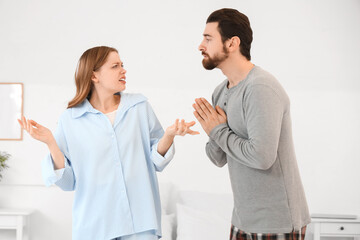 Fototapeta premium Young man apologizing to his angry wife in bedroom