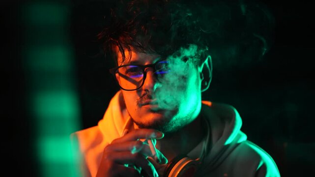 Computer Programmer or Hacker Smoking Cigarette in Front of Glitching Screen in Dark Room