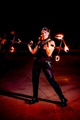 Fire artist captivating the audience while performing with a flaming staff at night, creating a...