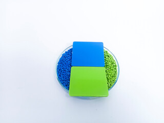 Masterbatch plastic, colorful polymer granules carrying pigments are poured into a glass cup with chips on a white background, suitable for product catalog design of industrial plastic company profile
