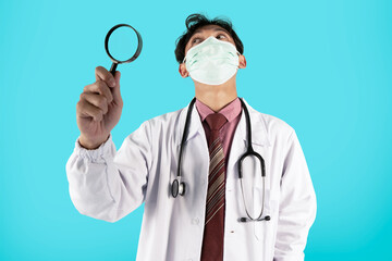 portrait of a male doctor wearing doctor's white coat using magnifying glass and medical mask