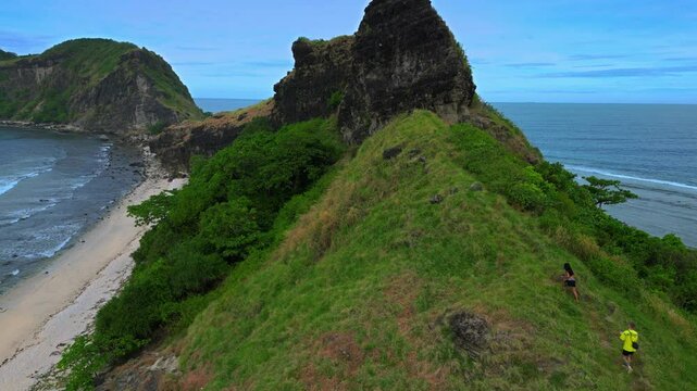 A couple of travellers are hiking the mountain range at Capones Island, Pundaquit beach. Zambales, Philippines