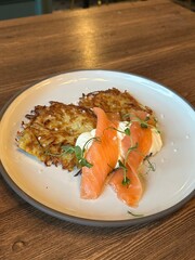 Potato pancakes with sour cream and salmon. Restaurant serving of dishes. Vertical