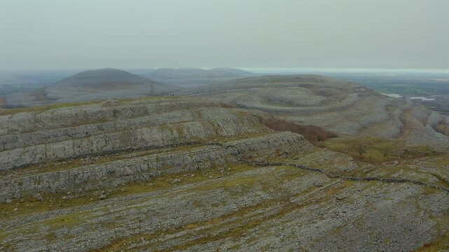 Hikers atop Mullaghmore peak, aerial showcasing stunning views. County Clare.