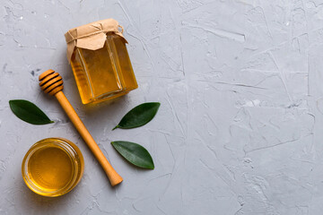 Honey jar with wooden honey dipper on white background top view with copy space. Delicious honey bottle