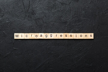 Microaggressions word written on wood block. Microaggressions text on cement table for your desing,...