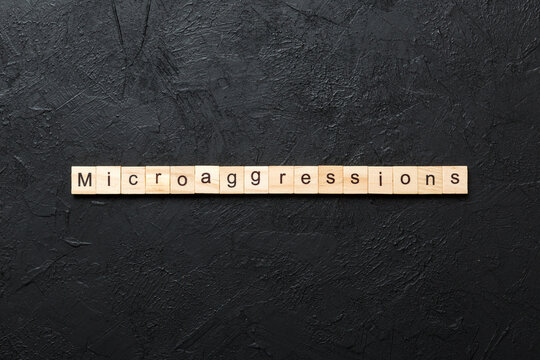 Microaggressions word written on wood block. Microaggressions text on cement table for your desing, concept