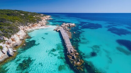 Stunning aerial view of a rocky jetty extending into vibrant turquoise waters under a clear blue sky