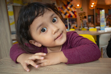 Smiling toddler girl with wide eyes open with folded hands