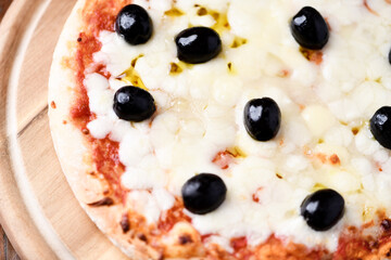 Pizza with mozzarella cheese and black olives on wooden background. Soft focus. Top view. Close up